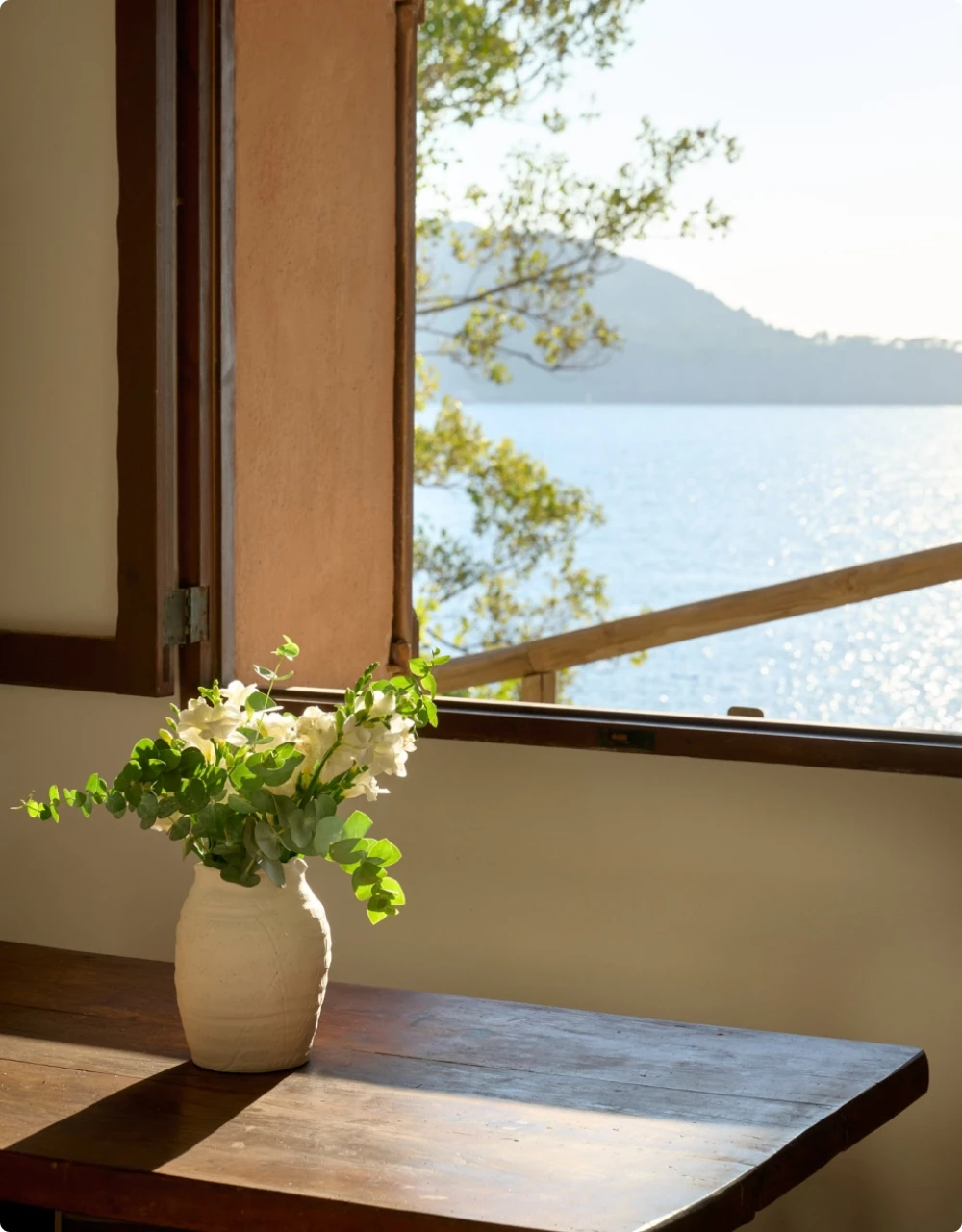 A vase of flowers with the backdrop of a window with an ocean view